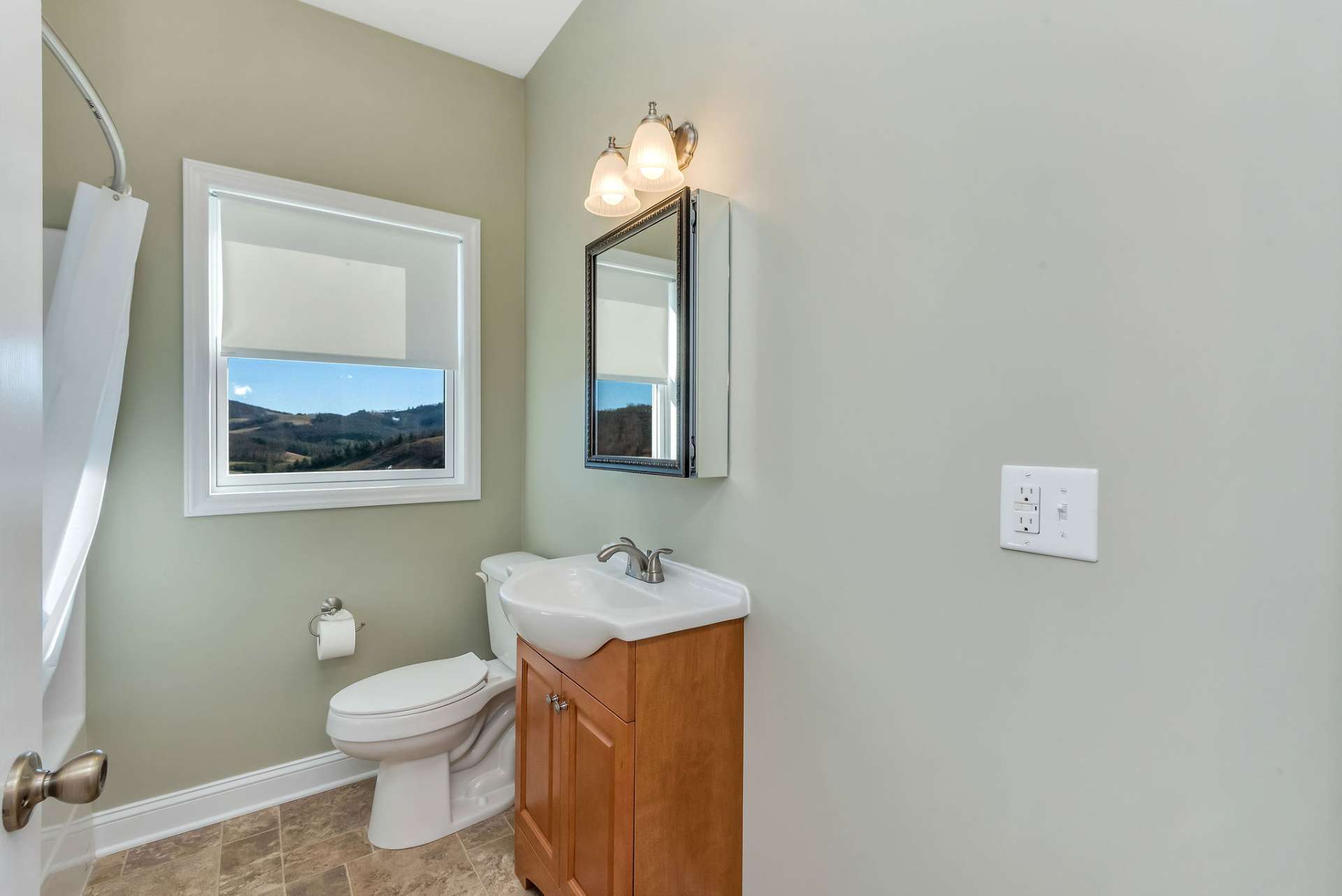 The guest full bath is beautifully designed to highlight the view through its window, offering a serene and picturesque touch.