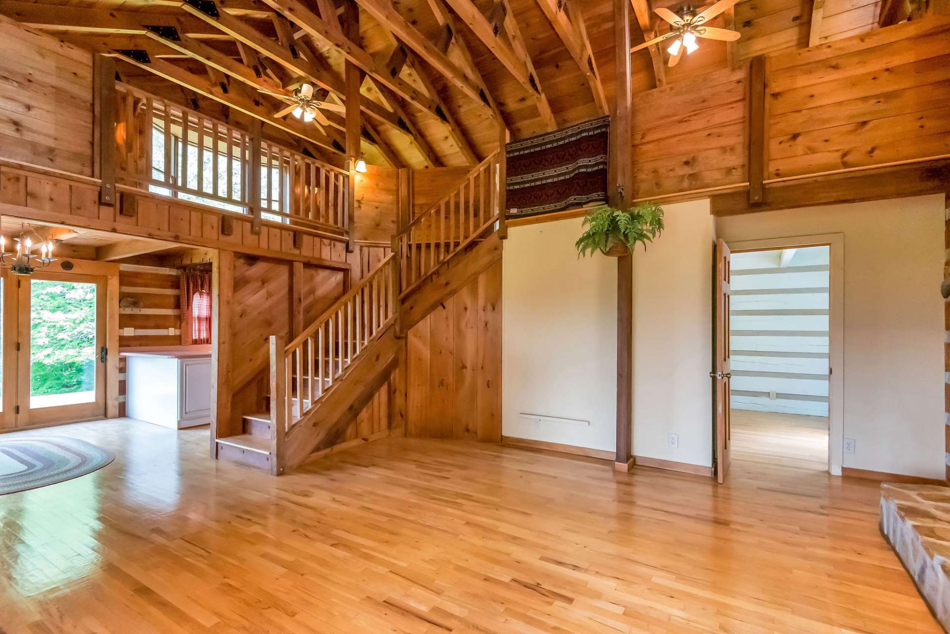 The open stairway and vaulted ceiling expand the sense of space, creating a lofty feel that complements the rustic charm of exposed beams overhead.