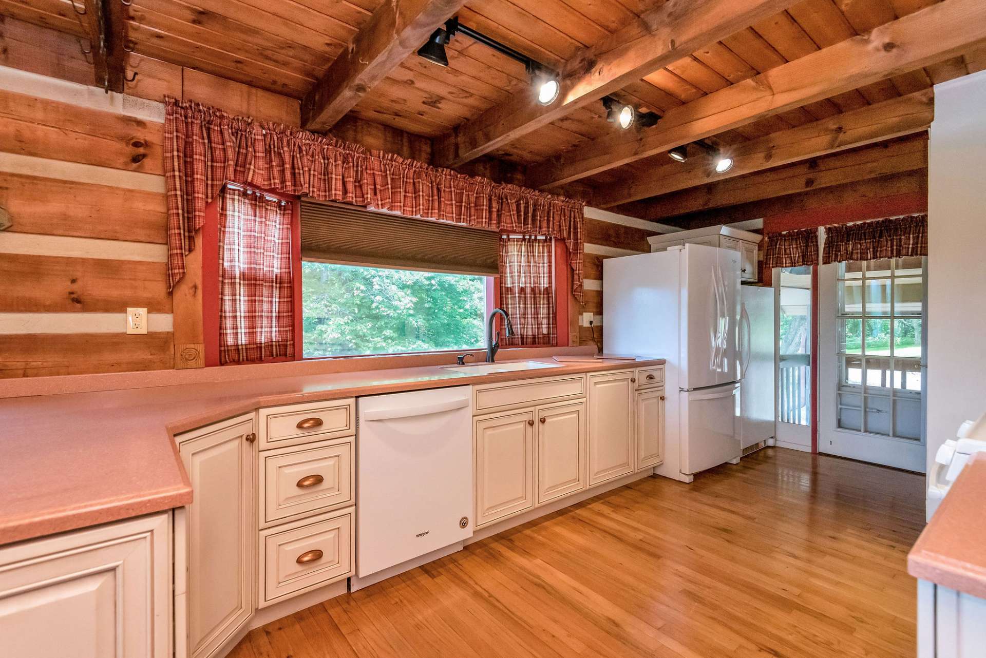 The hardwood flooring and exposed beams continue seamlessly through the kitchen, maintaining the rustic charm and creating a cohesive aesthetic throughout the space.