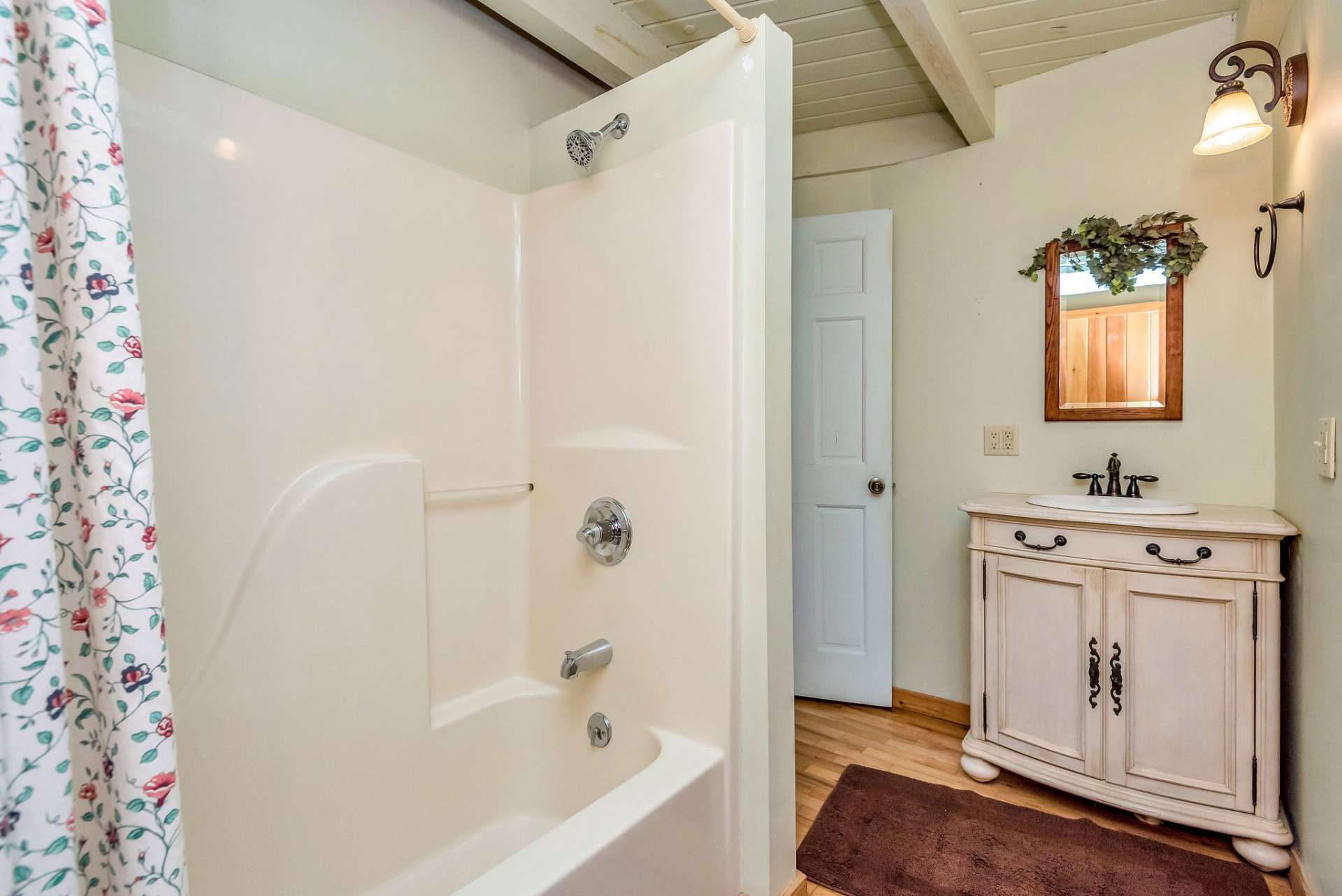 The main level bath features a fiberglass tub/shower, a single vanity, and a convenient laundry area, offering practicality and comfort in one space.