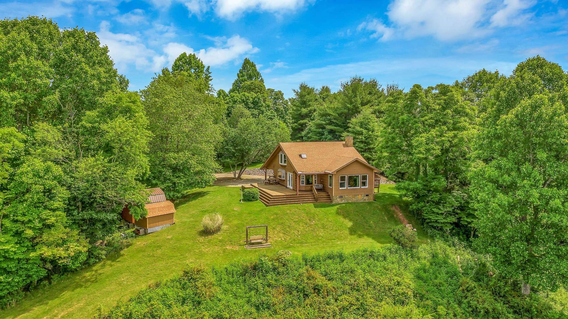 This mountain sanctuary is wired for a generator, boasts a convenient circle drive, and includes three outbuildings for additional storage or workspace.