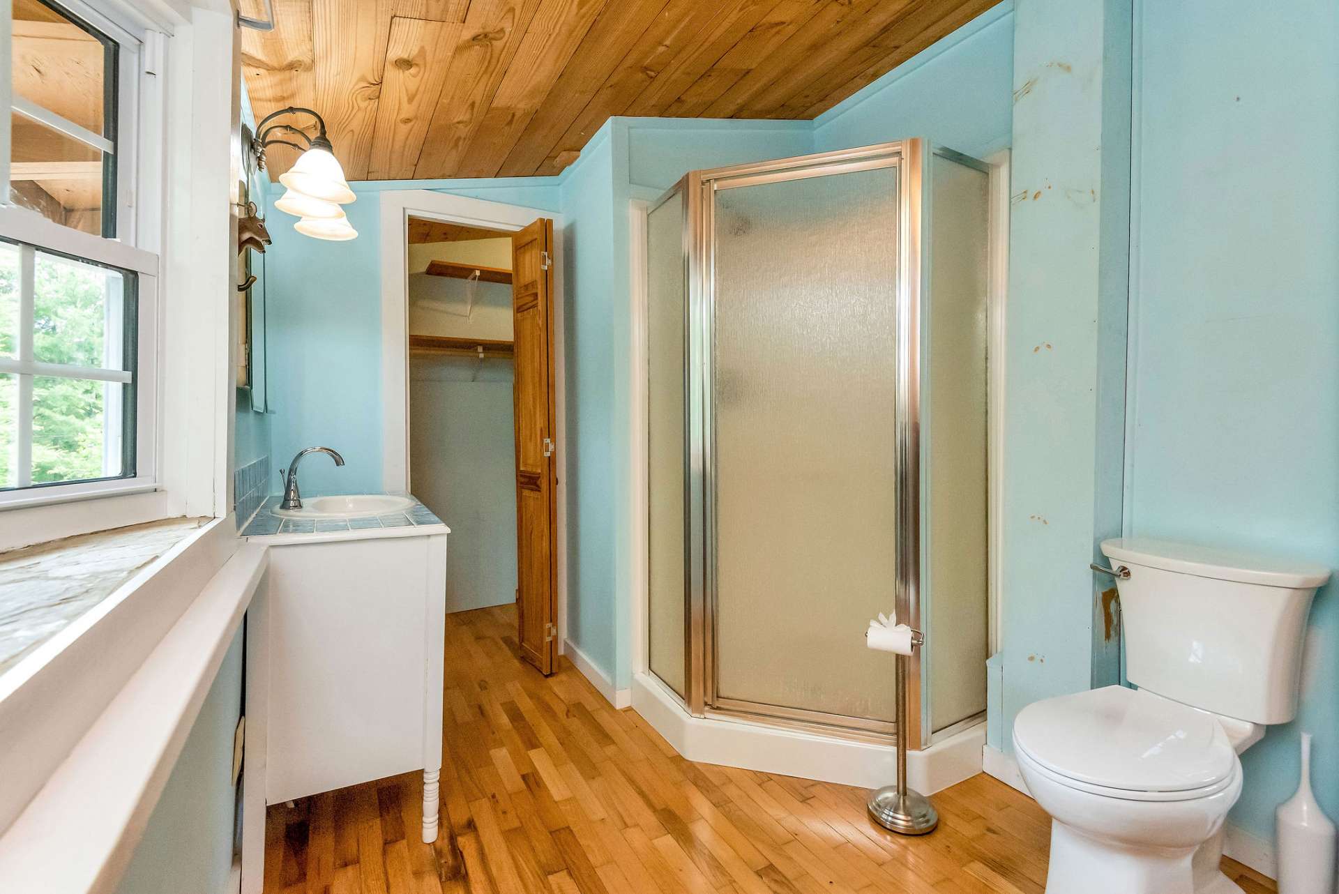 The upper-level bathroom features a walk-in shower and a unique vanity crafted from an antique dresser, adding character to the space.