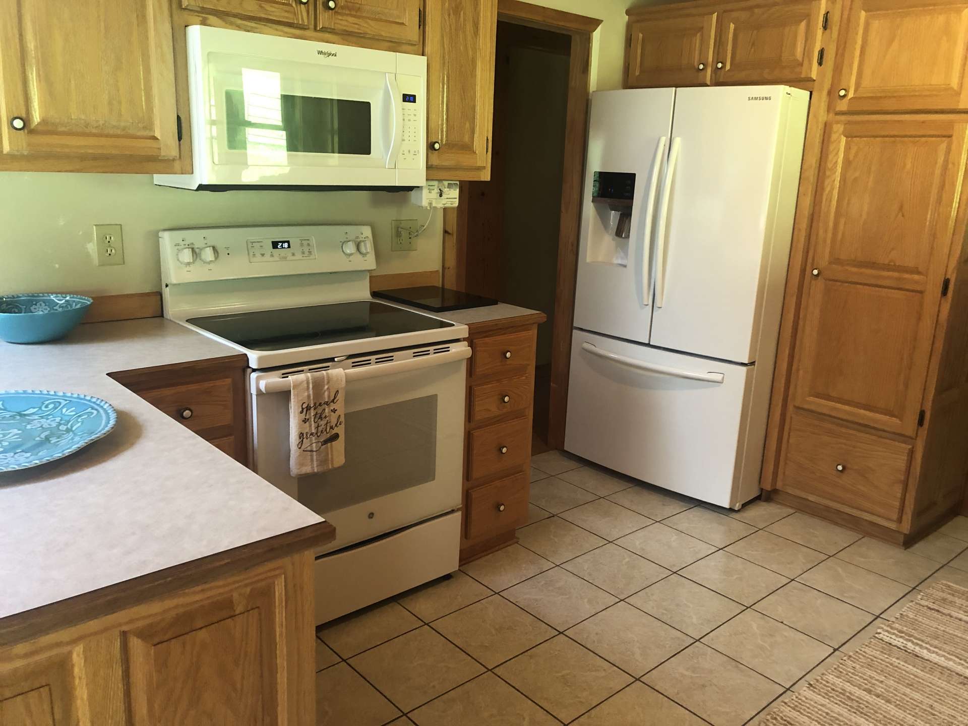 Kitchen features range with microwave over, oversized refrigerator, and pantry