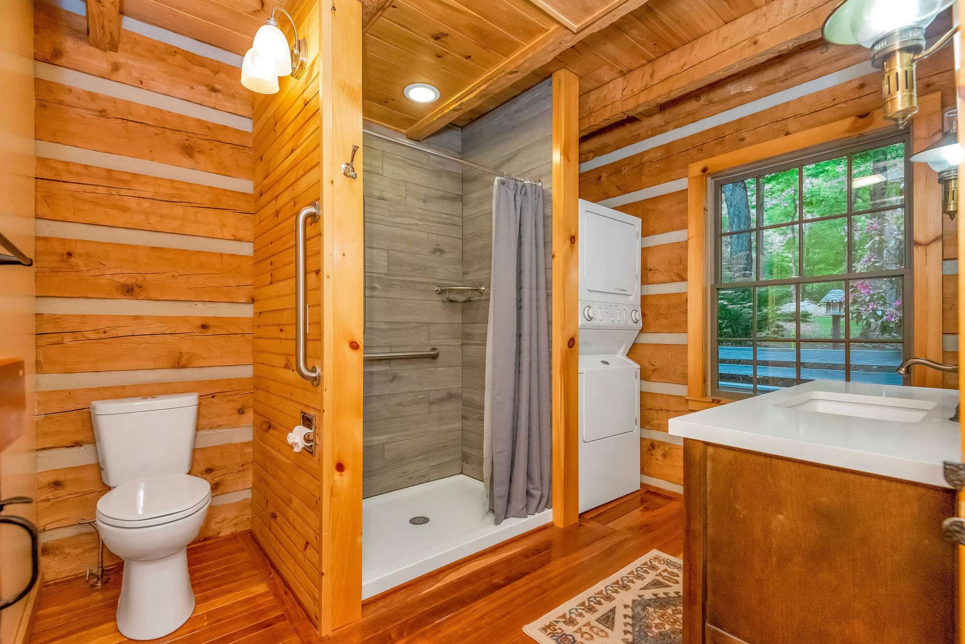 The main level bath is designed for both functionality and style, featuring a tile shower, washer/dryer, and an updated vanity that blends rustic charm with elegant touches.