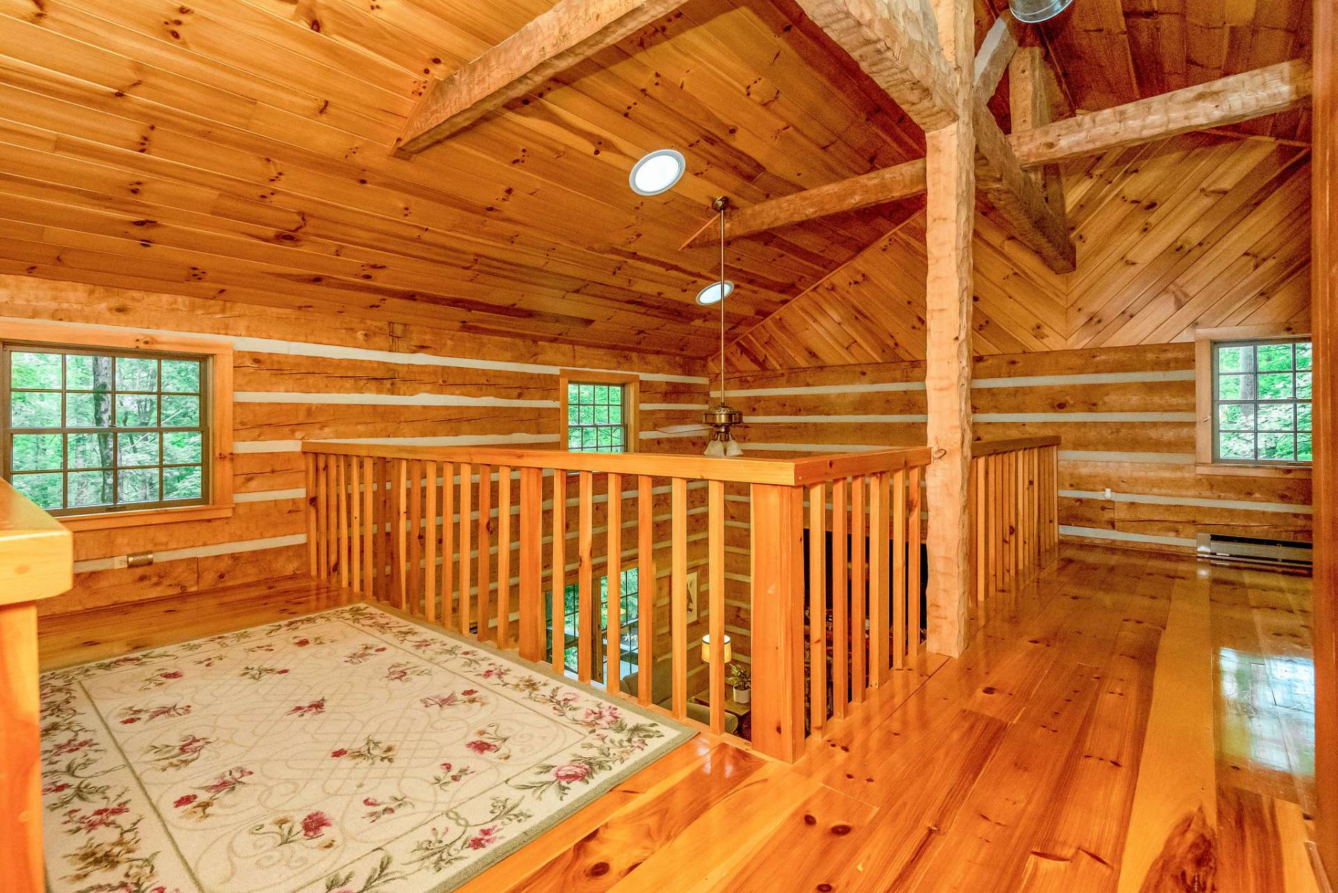 The loft provides a view overlooking the living area below, offering a sense of openness and connectivity between the different levels of the cabin.