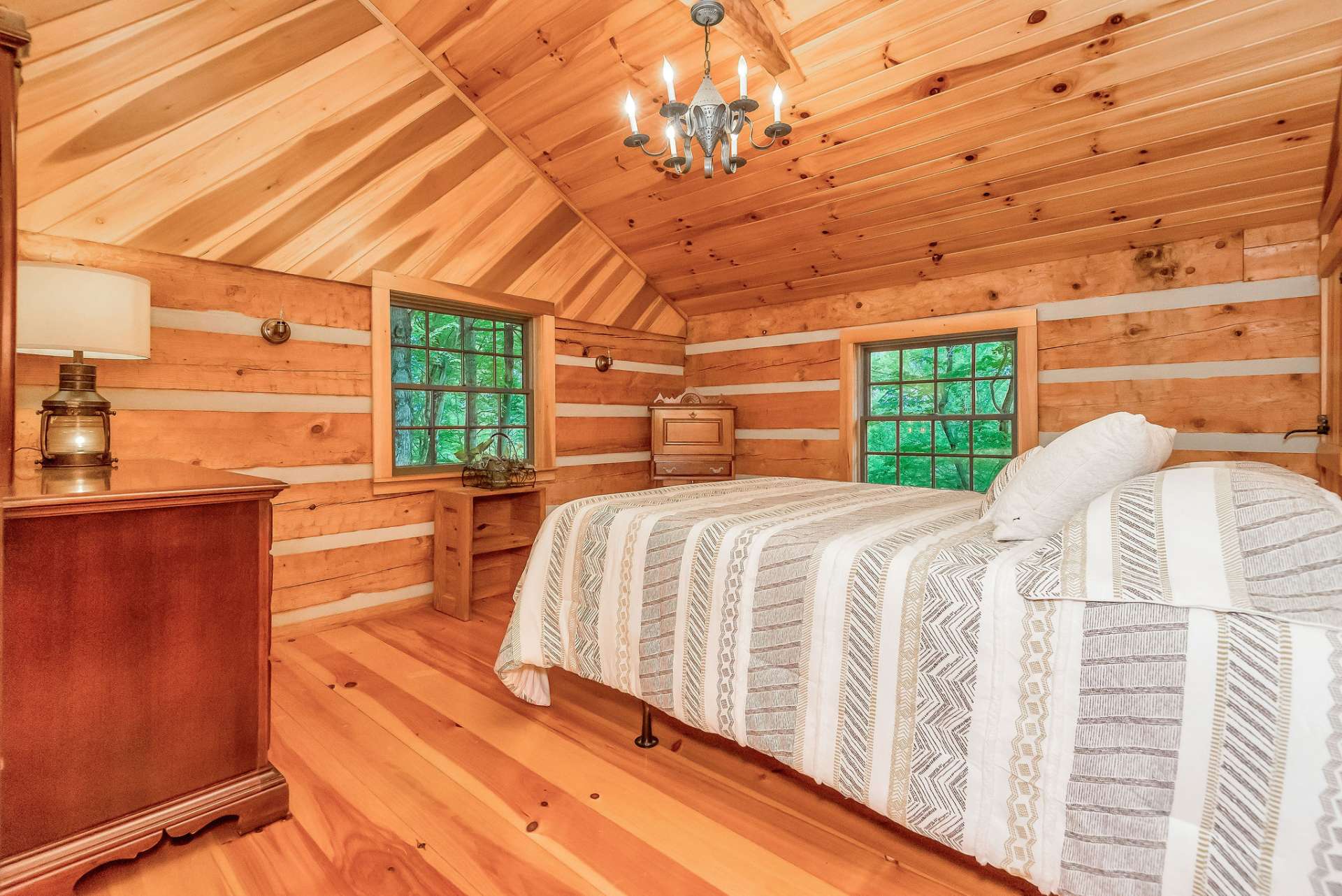 The upper-level guest room features a vaulted ceiling, adding to the sense of spaciousness and airiness in the space.