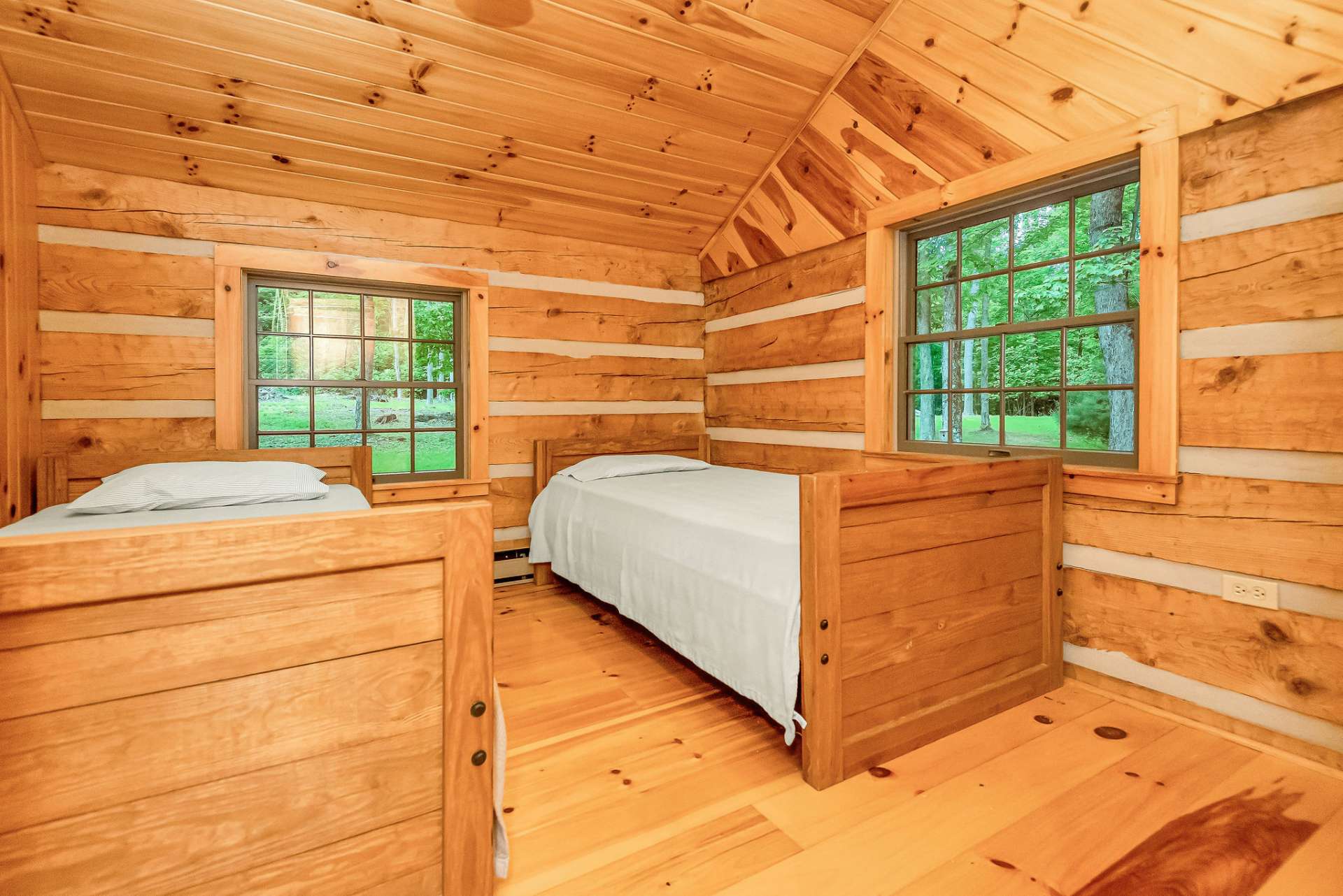 The second bedroom on the upper level also features a vaulted ceiling and a picturesque view into the surrounding forest, bringing the beauty of nature indoors.