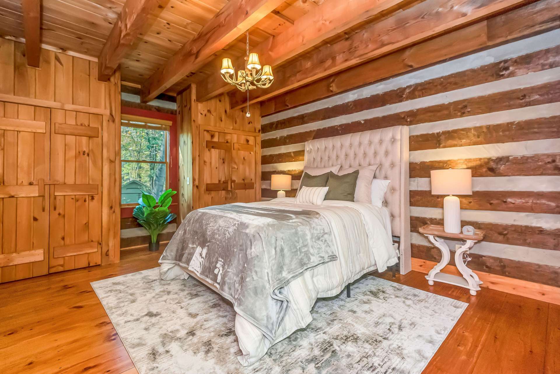 The inviting main-level bedroom exudes rustic charm with its exposed log walls and warm wood tones.